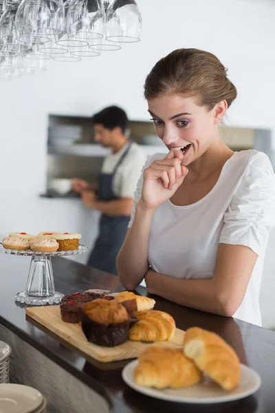 女人看着甜的食物，在咖啡店里 — 图库照片