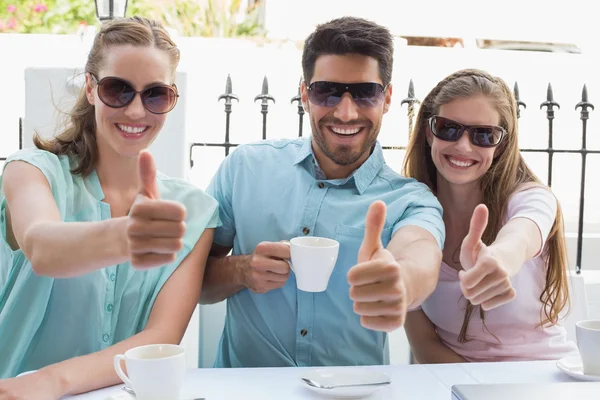 Happy friends gesturing thumbs up in cafe — Stock Photo, Image