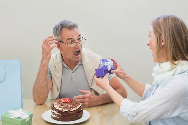 テーブルでケーキを贈り物を授かるとショックを受けた男 — ストック写真