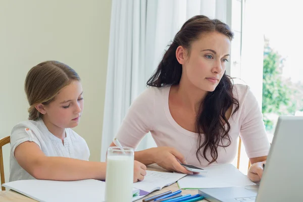 Woman using technologies while daughter studying at table — Stock Photo, Image