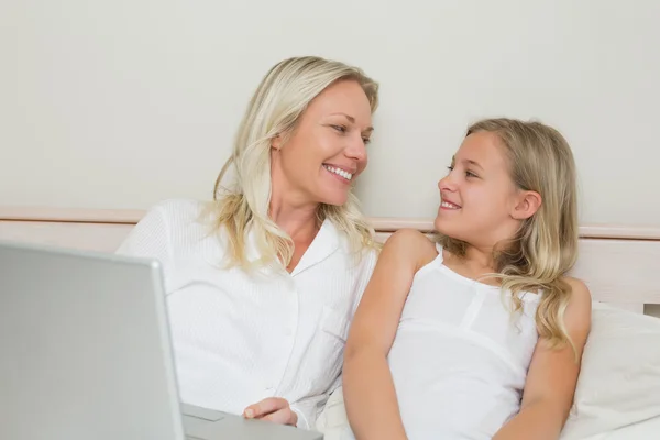 Mère et fille détendues avec ordinateur portable au lit — Photo