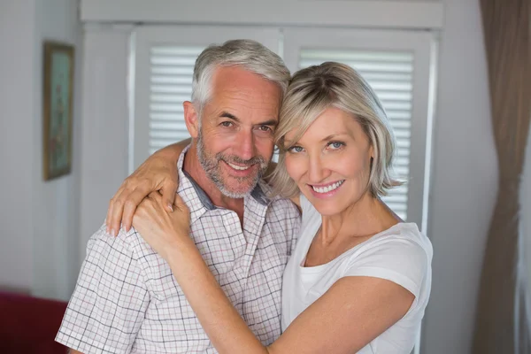 Smiling woman embracing mature man at home — Stock Photo, Image