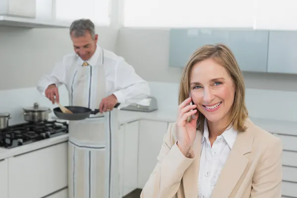 Businesswoman on call while man preparing food in kitchen — Stock Photo, Image