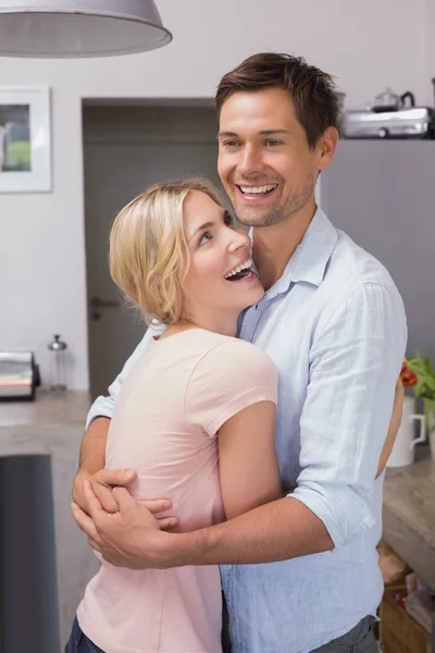 Feliz joven pareja abrazándose en la cocina — Foto de Stock