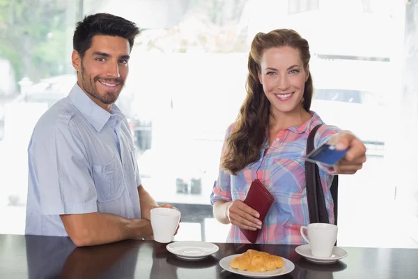 Pareja con mujer sosteniendo la tarjeta de crédito en la cafetería — Foto de Stock