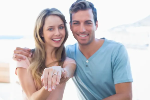 Happy woman showing engagement ring besides man — Stock Photo, Image