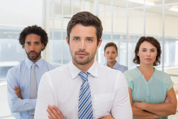 Hombre de negocios serio de pie con sus colegas en el cargo — Foto de Stock