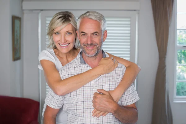 Lächelnde Frau umarmt reifen Mann zu Hause — Stockfoto