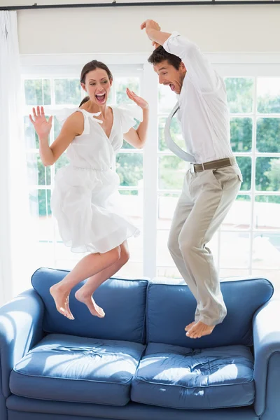 Glada unga par hoppa på soffan — Stockfoto