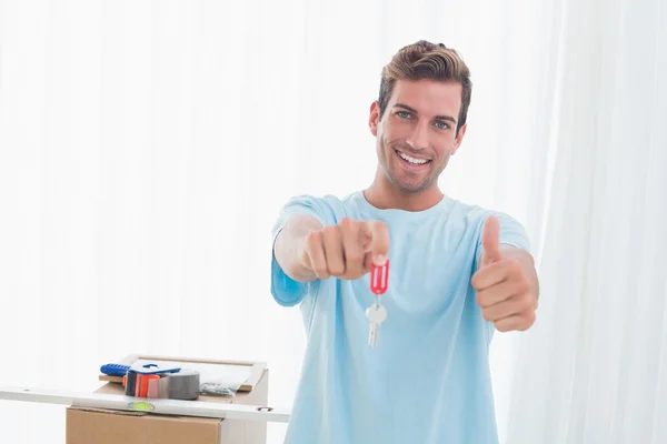 Hombre sosteniendo la nueva llave de la casa mientras gesticulando pulgares hacia arriba — Foto de Stock