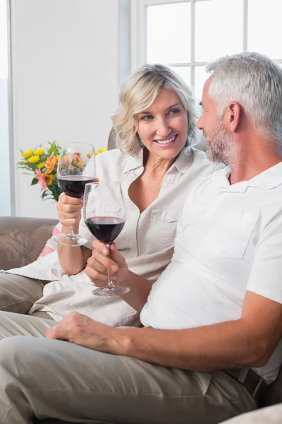 Gelukkige volwassen paar met wijn glazen in woonkamer — Stockfoto