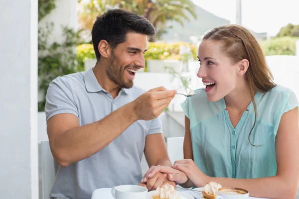 Hombre feliz alimentando a la mujer en la cafetería — Foto de Stock