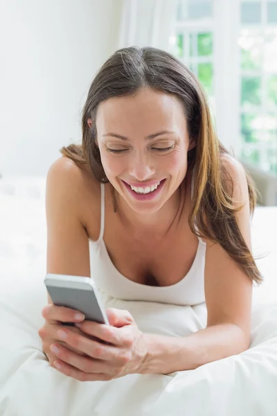 Lachende vrouw van het tekstoverseinen in bed — Stockfoto