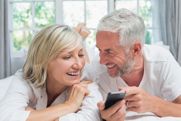 Cheerful mature couple reading text message at home — Stock Photo, Image
