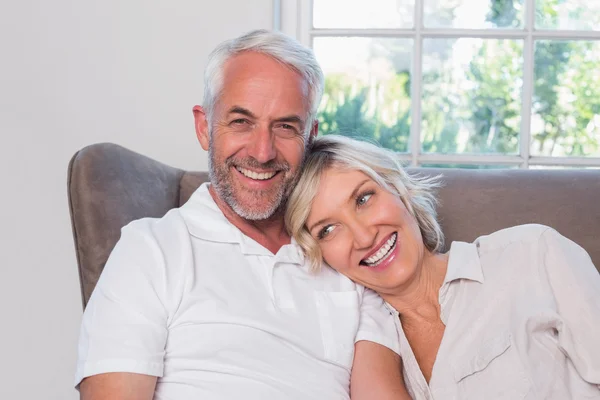 Retrato de una pareja madura sonriente sentada en un sofá — Foto de Stock