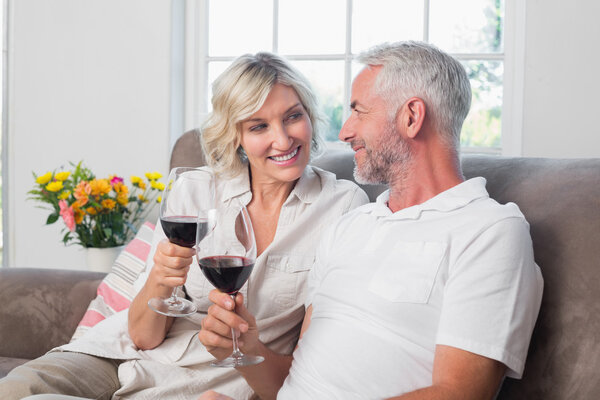 Happy loving mature couple with wine glasses in living room