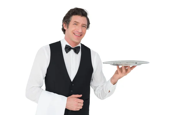 Felice cameriere tenendo vassoio contro sfondo bianco — Foto Stock