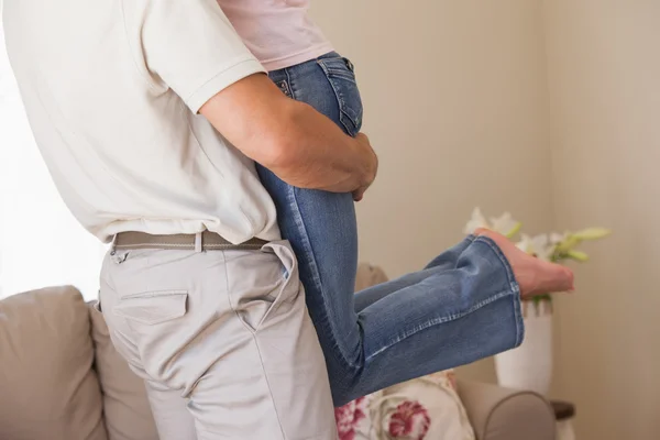 Hombre llevando mujer en sala de estar — Foto de Stock