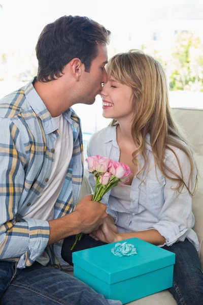 Ung man kysser kvinna med blommor och presentförpackning — Stockfoto