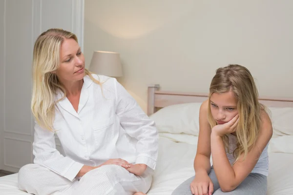 Frau sieht trauriges Mädchen auf Bett sitzen — Stockfoto