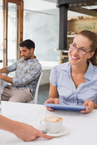 Mujer sonriente recibiendo café mientras usa la tableta digital en la cafetería —  Fotos de Stock