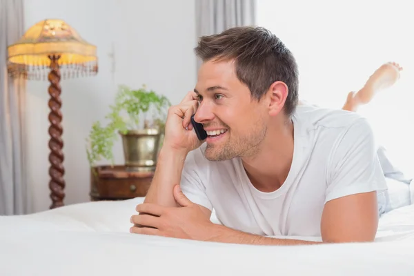 Avslappnad avslappnad man använder mobiltelefon i sängen — Stockfoto