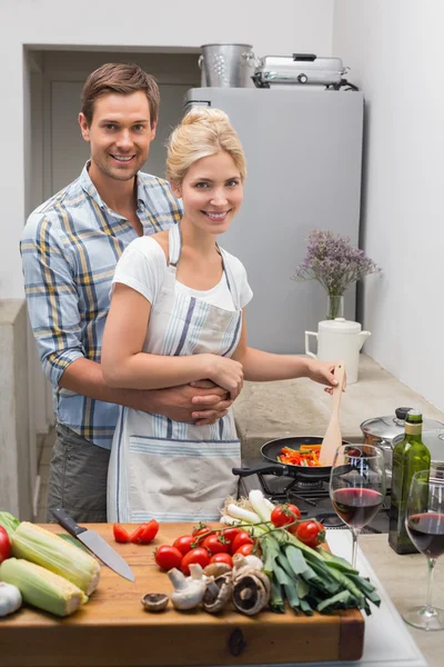 Jovem casal preparando comida juntos na cozinha — Fotografia de Stock