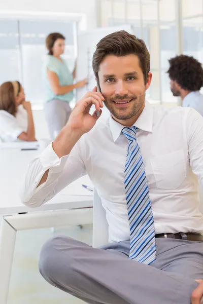 Smiling businessman on call with colleagues at office — Stock Photo, Image