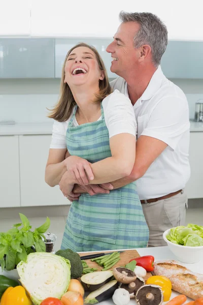 Vista lateral de un hombre abrazando mujer en la cocina — Foto de Stock