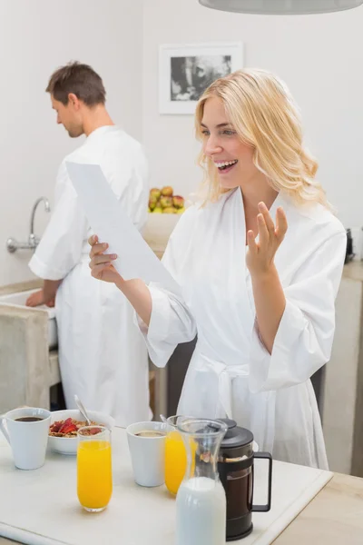 Donna sorridente guardando il documento con l'uomo in cucina — Foto Stock