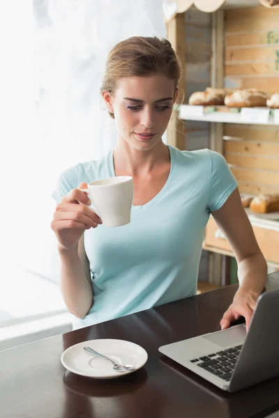 Mulher com xícara de café usando laptop no café — Fotografia de Stock