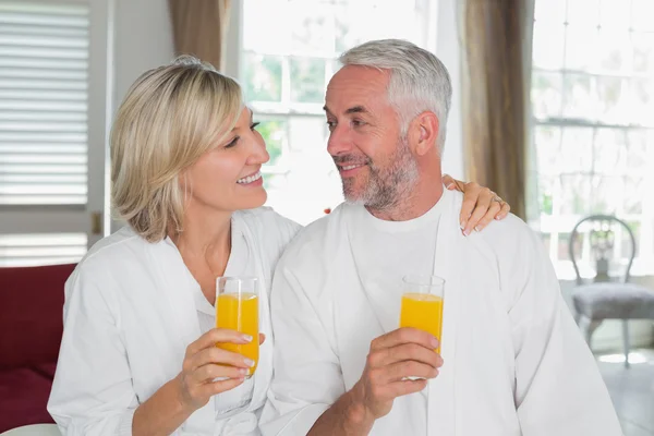 Feliz casal maduro segurando sucos de laranja — Fotografia de Stock
