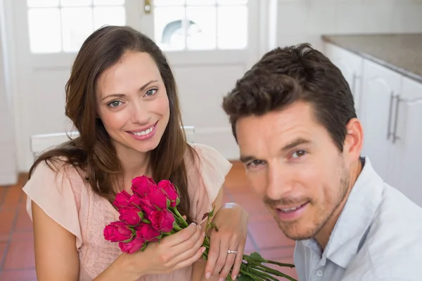 Joyeux jeune couple avec des fleurs à la maison — Photo