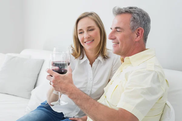 Casal relaxado com copos de vinho sentado no sofá — Fotografia de Stock
