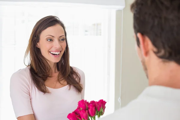 Веселая женщина смотрит на мужчину с цветами — стоковое фото