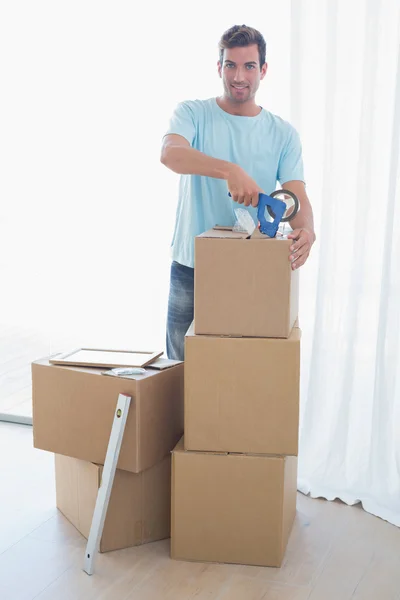 Young man with cardboard boxes in new house — Stock Photo, Image