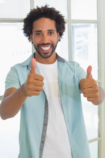 Smiling casual businessman gesturing thumbs up in office — Stock Photo, Image