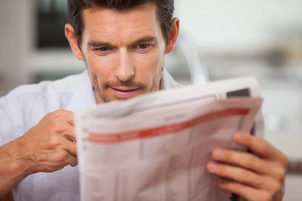 Konzentrierter junger Mann liest Zeitung — Stockfoto