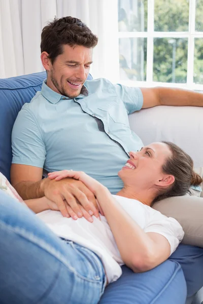 Mulher feliz descansando no colo do homem no sofá — Fotografia de Stock