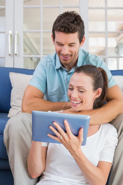 Happy couple using digital tablet on couch — Stock Photo, Image