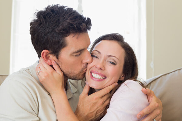 Loving young man kissing woman in living room