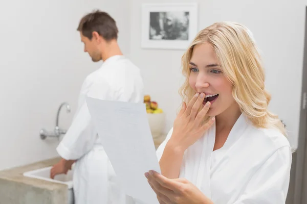 Здивована жінка дивиться на документ з чоловіком на кухні — стокове фото