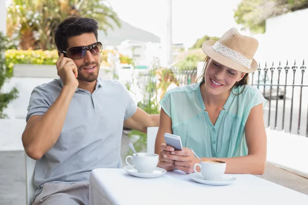 Glückliches Paar mit Mobiltelefonen im Café — Stockfoto