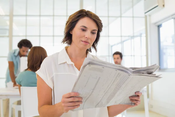 Affärskvinna läsa tidningen med kollegor i mötet — Stockfoto