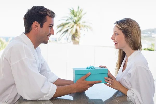 Mannen ger kvinnan presentförpackning hemma — Stockfoto