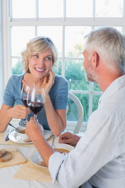 Glückliches reifes Paar beim Anstoßen von Getränken über Essen — Stockfoto