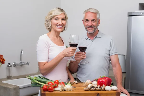 Pareja madura tostando copas de vino mientras prepara la comida —  Fotos de Stock