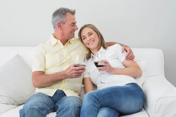 Coppia con bicchieri di vino seduti sul divano — Foto Stock