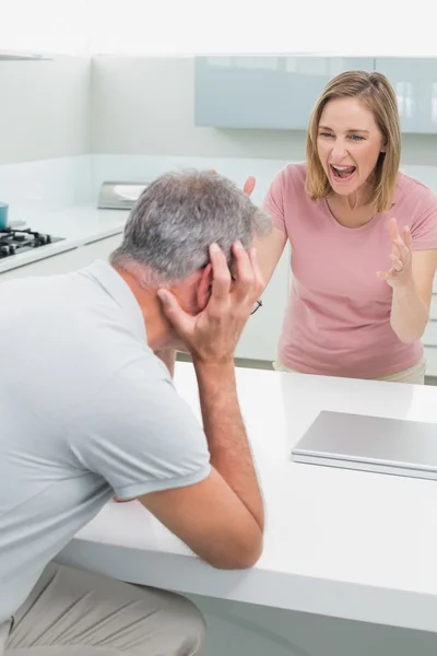 Woman screaming at man as he covers his ears in kitchen — Stock Photo, Image