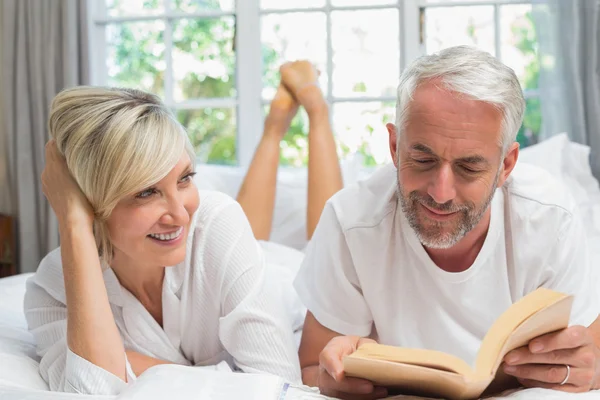 Happy mature couple reading book in bed — Stock Photo, Image